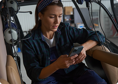 Crew member checking FlightApp on her phone in a helicopter cabin